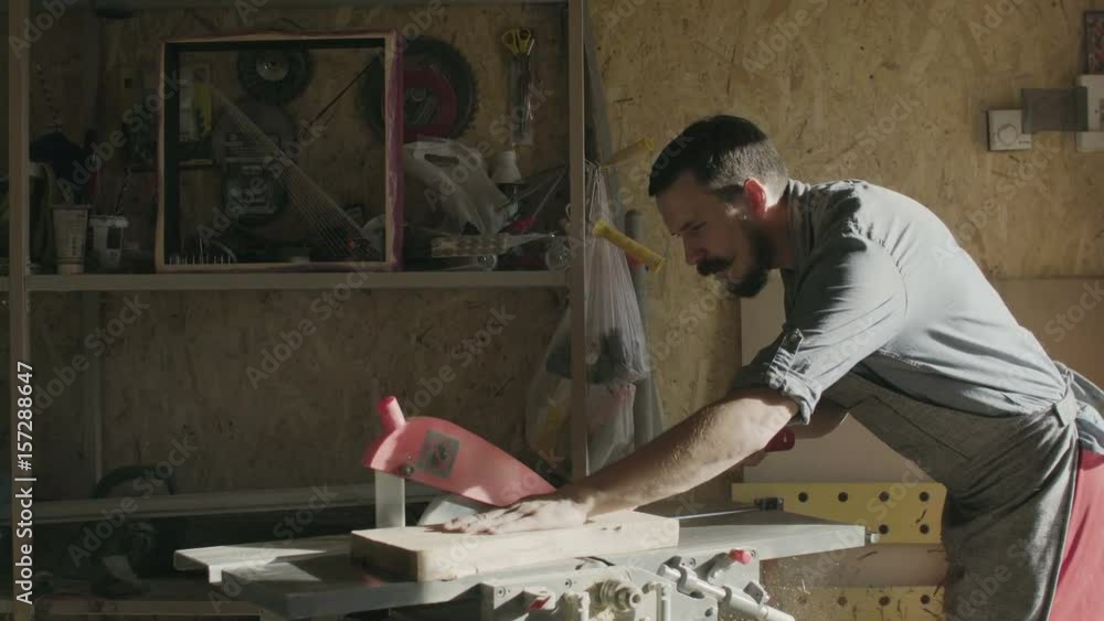 Woodworker is working with wooden plank at his workshop. sunny day Woodworker is working with wooden plank at his workshop. sunny day