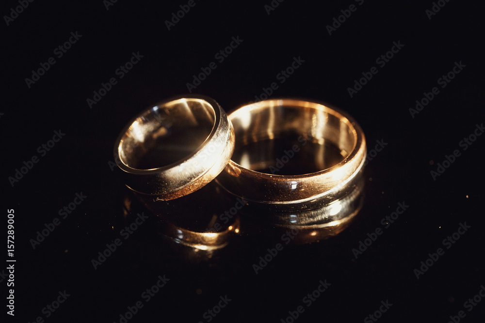 Sparkling wedding rings lie on glass table Sparkling wedding rings lie on glass table