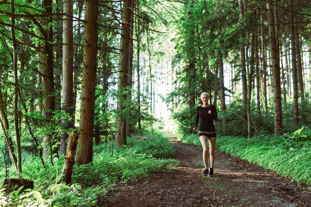 Woman running through forest in black clothes Woman running through forest in black clothes