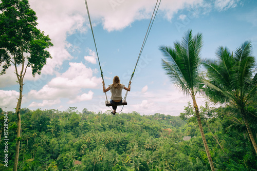 Young attractive girl swinging in nature.