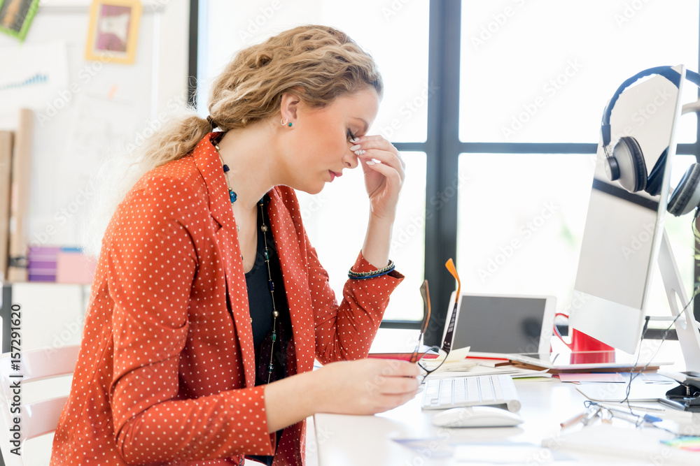 Obraz premium Young woman in office tired