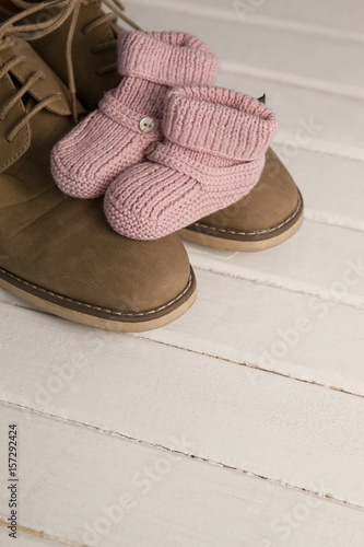 Baby booties with mans shoes on floor photo