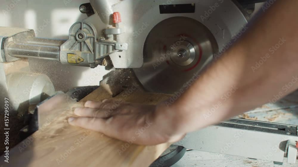 Close up hands of carpenter neg wooden plank using circular saw. flying sawdust Close up hands of carpenter neg wooden plank using circular saw. flying sawdust