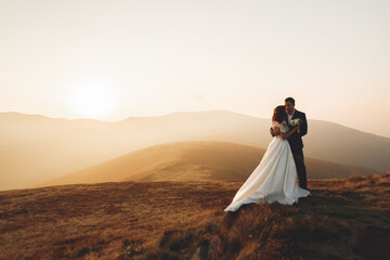 Wedding couple posing on sunset at wedding day. Bride and groom in love