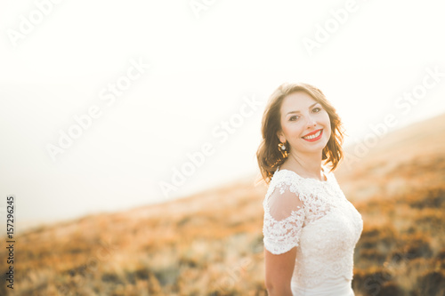Happy beautiful bride outside on a summer meadow at the sunset with perfect view