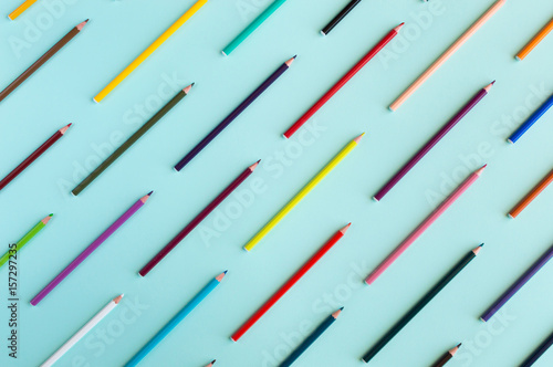 Colorful background with many crayons pastels lined up on azure aquamarine - Top view flat lay