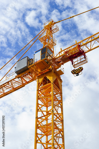 Wallpaper Mural Orange construction tower crane with jib and hook isolated on blue sky with white clouds background, detail Torontodigital.ca