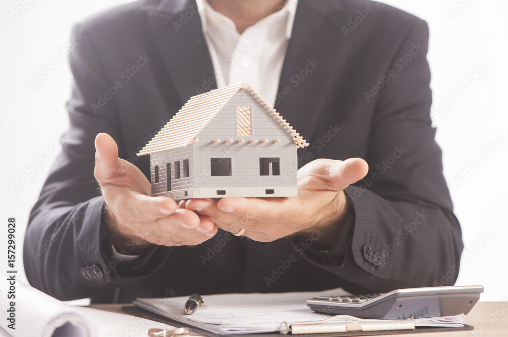 Businessman Holding Model House In Palm Of Hand Businessman Holding Model House In Palm Of Hand