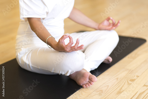 Young woman sitting cross legged on the floor doing yoga