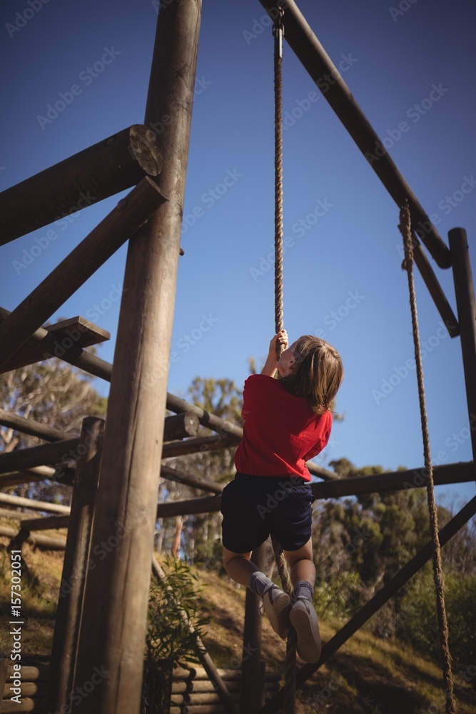 Determined girl climbing rope during obstacle Determined girl climbing rope during obstacle