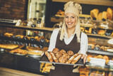 Female bakery posing with various types of pastries and breads in the baker shop