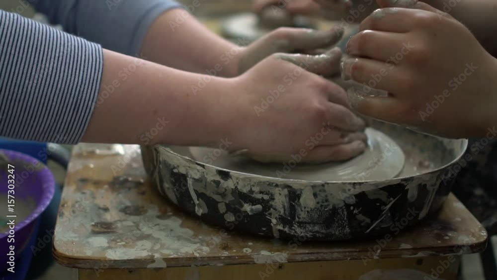 Master and pupil trying to make a pitcher on pottery wheel in a workshop. Master and pupil trying to make a pitcher on pottery wheel in a workshop.