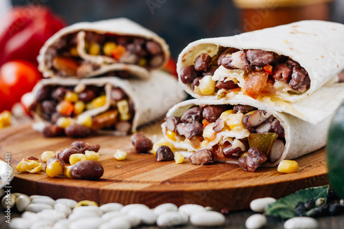 Nice vegetarian burrito over black table on wooden board. photo