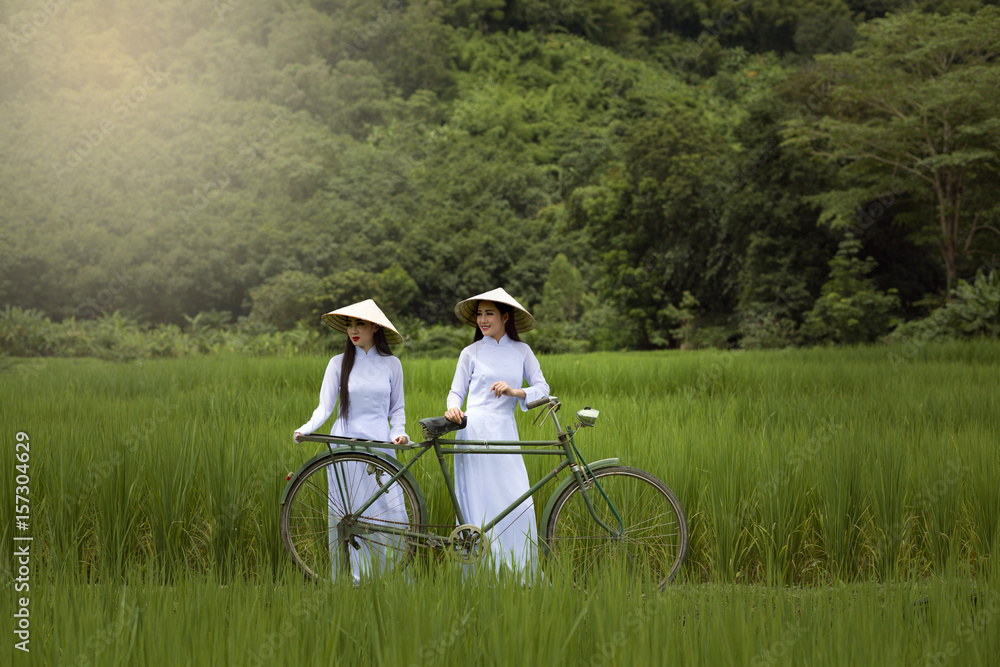 Asia beautiful women in Ao Dai Vietnam traditional dress and bicycle in green rice field this is the best culture of Vietnam. Asia beautiful women in Ao Dai Vietnam traditional dress and bicycle in green rice field this is the best culture of Vietnam.