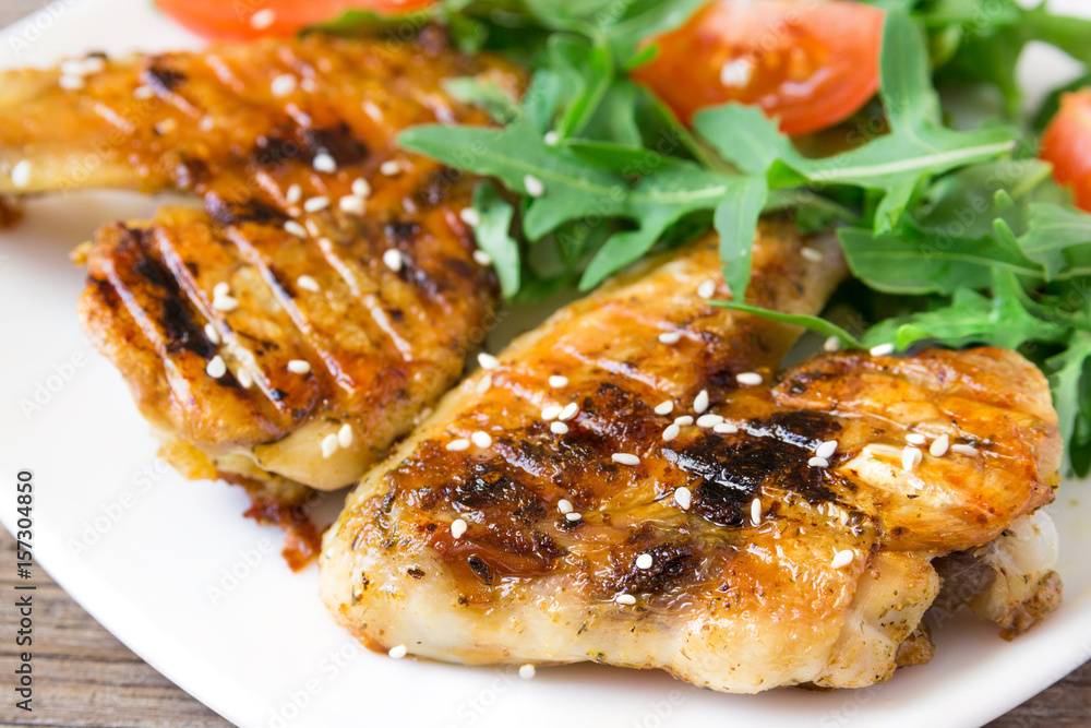 Spicy grilled chicken wings and vegetables  on rustic background.