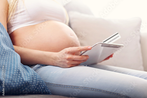 Pregnant woman using tablet at home