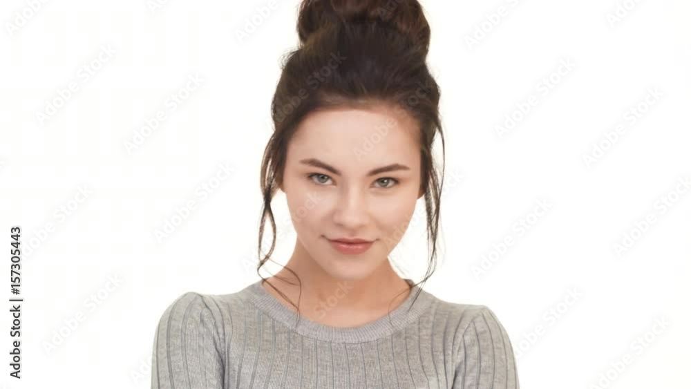 Beautiful Caucasian brunette girl looking straight at camera and pointing to look right into eyes. Footage on white background