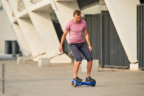 Young man on hoverboard outdoors. Guy riding gyroscooter.