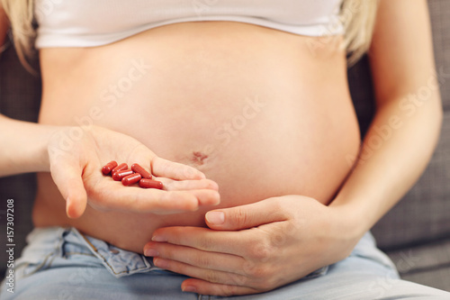 Pregnant woman holding pills at home
