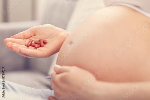 Pregnant woman holding pills at home