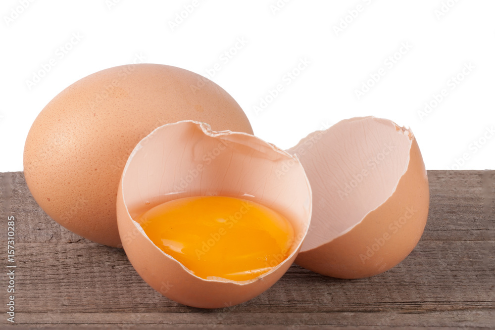 Broken egg with yolk and eggshell on a wooden table with a white background Broken egg with yolk and eggshell on a wooden table with a white background