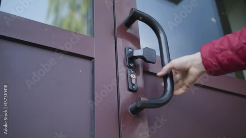 A hand is checking a dark pink door. The door is closed Close-up shot. photo