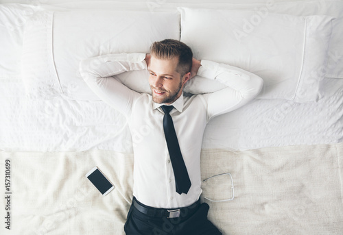 Top view. Handsome businessman relaxing on bed after a tough day at work