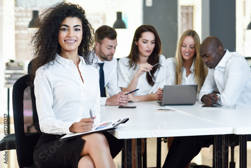 Multi-ethnic group of three businesspeople meeting in a modern office.