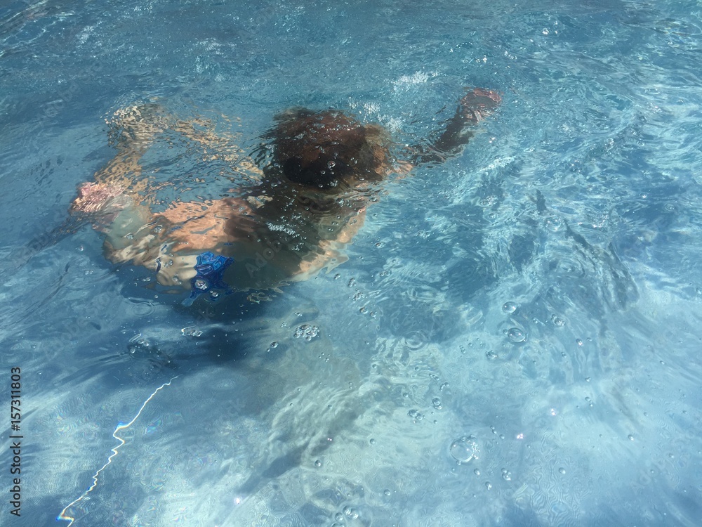 Kind spielt und taucht in blauem Wasser