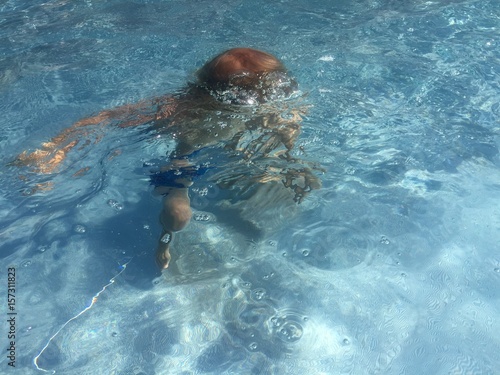 Kind spielt und taucht in blauem Wasser