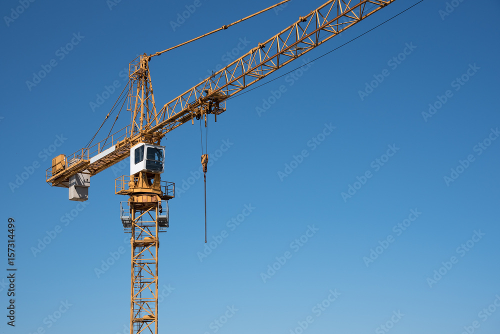 A yellow crane on a construction site with blue sky A yellow crane on a construction site with blue sky