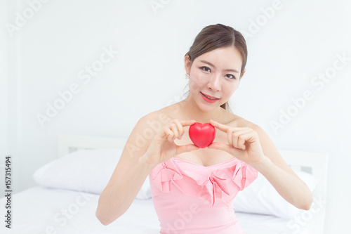 Beautiful korea woman holding with heart on bed.
