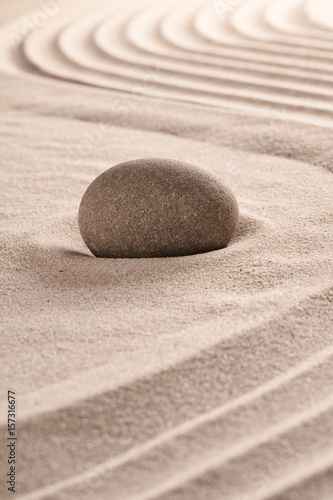 Purity concept by round stone on raked sand in zen meditation garden.