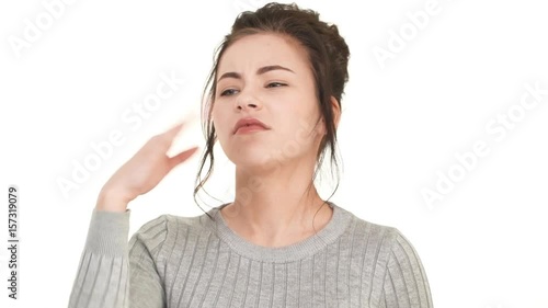 Young Caucasian girl with brunette hair standing on white background and smelling something bad in air in slowmotion