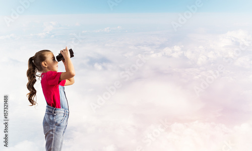 Concept of careless happy childhood with girl looking in binoculars