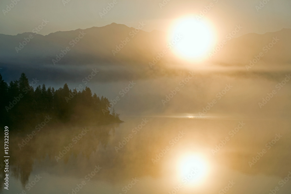 Fog on the mountain lake and the rising sun. Yakutia, lake Darpir.
