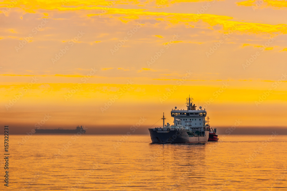 Tanker and tugboat on sea early morning just before sunrise.