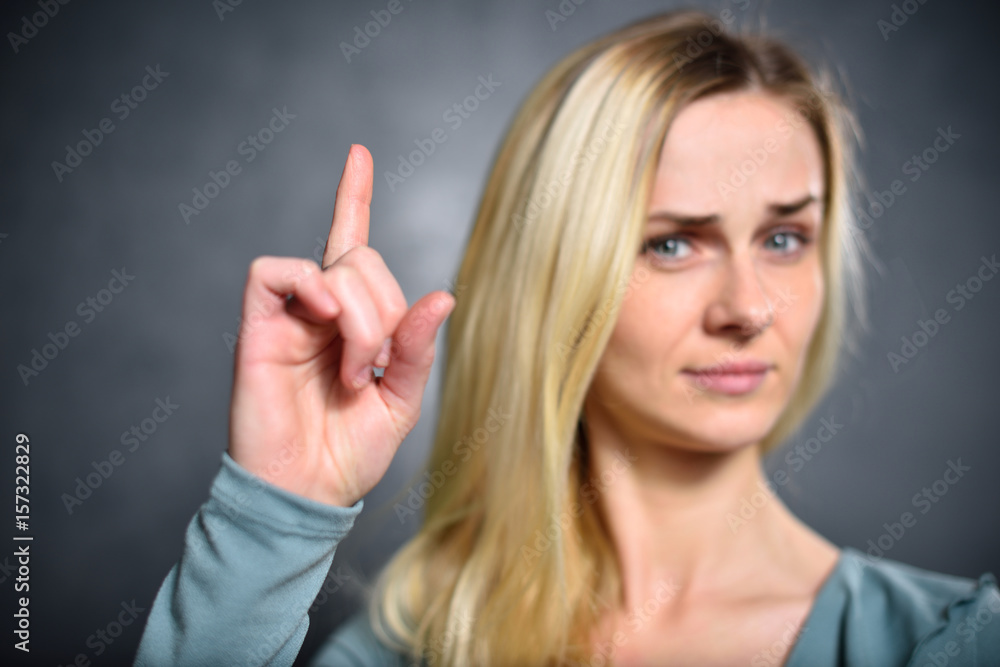 Girl shows up an index finger, expressing a sign of attention Girl shows up an index finger, expressing a sign of attention