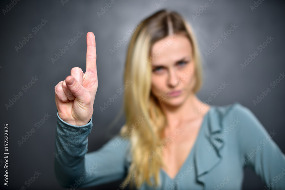Girl shows up an index finger, expressing a sign of attention Girl shows up an index finger, expressing a sign of attention