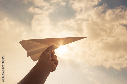 Taking flight! hand holding paper airplane in the sky. 