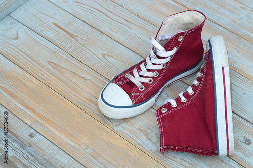 grunge wooden background with red vintage canvas sneakers


