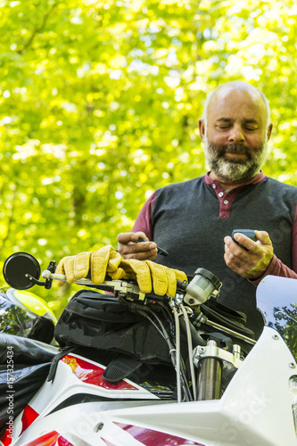 Mature, diabetic man testing his blood sugar beside his motorcycle