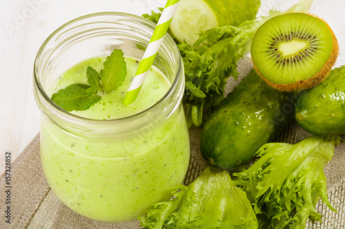 Healthy green smoothie in jar with cucumber, kiwi, salad and spices