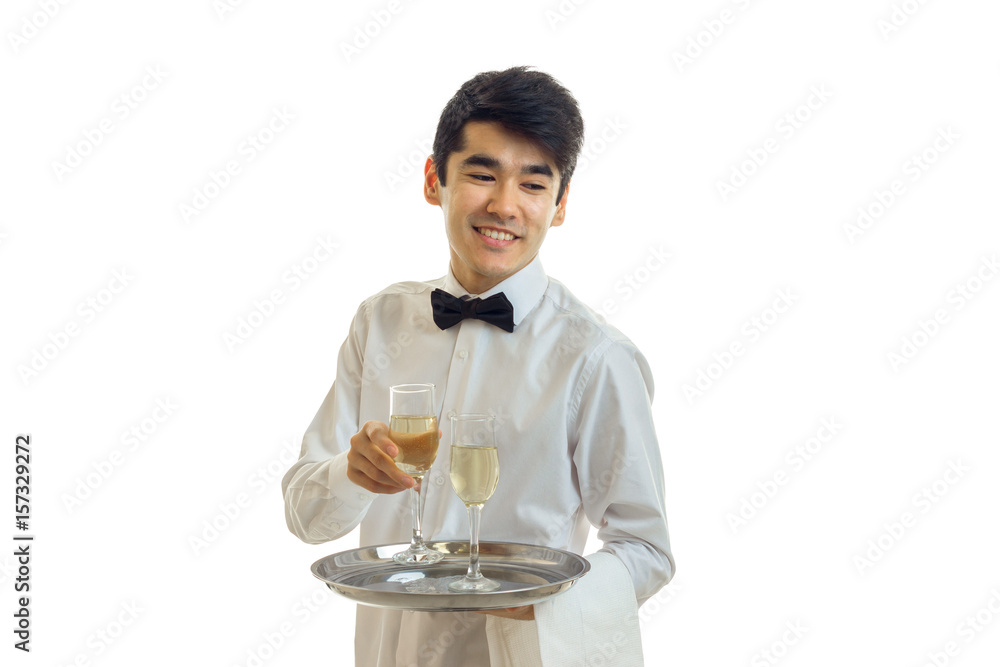 Cheerful man waiter in uniform and bowtie with glasses of white wine on silver tray smiling Cheerful man waiter in uniform and bowtie with glasses of white wine on silver tray smiling