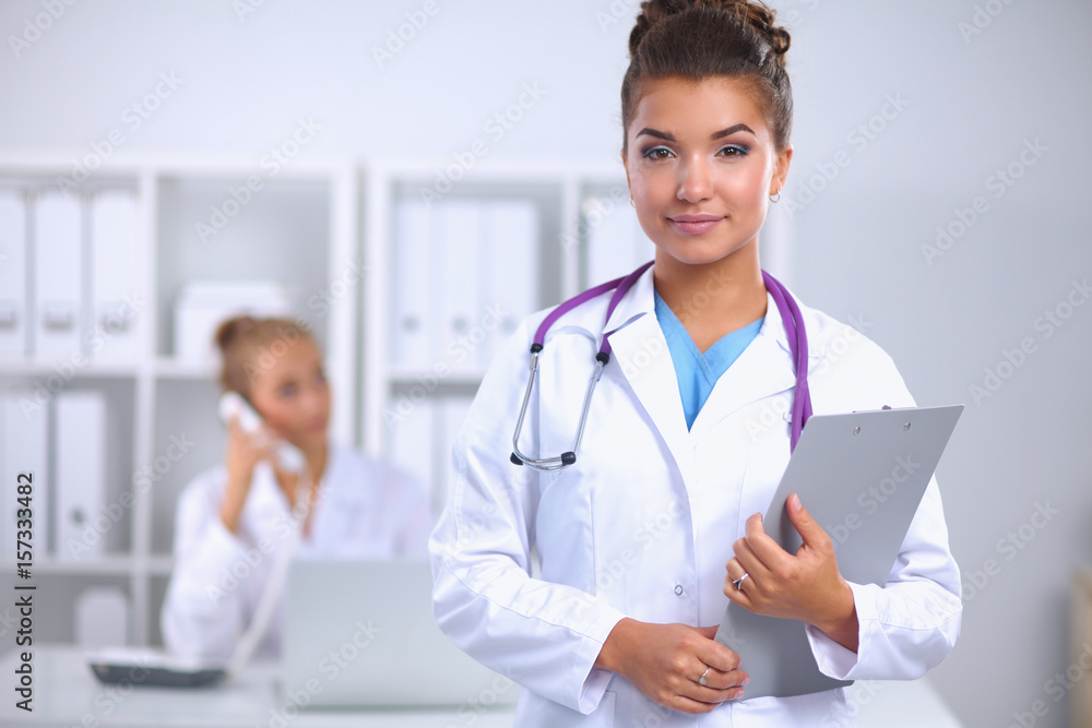 Smiling female doctor with a folder in uniform standing at hospital Smiling female doctor with a folder in uniform standing at hospital