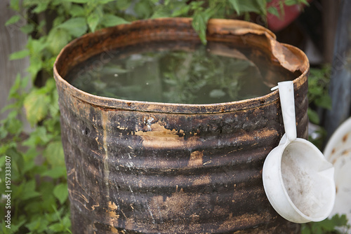 a rusty old barrel with water and a white bucket