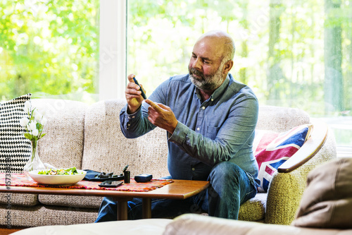 Mature, diabetic, ethnic man in his 50's checking his blood sugar