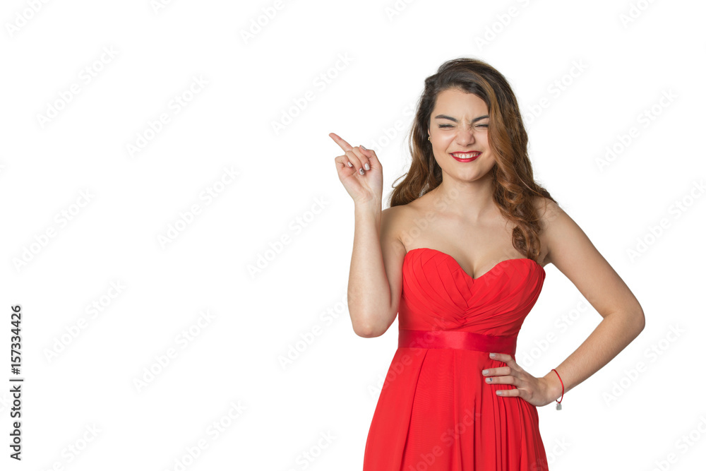 The girl in the red dress pointing to the side and laughing on an isolated background The girl in the red dress pointing to the side and laughing on an isolated background