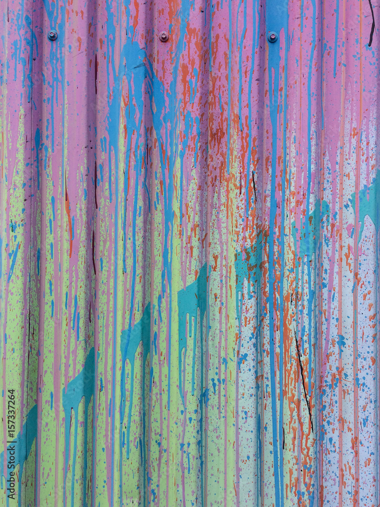 Abstract messy paint stains and splashes on corrugated metallic wall.