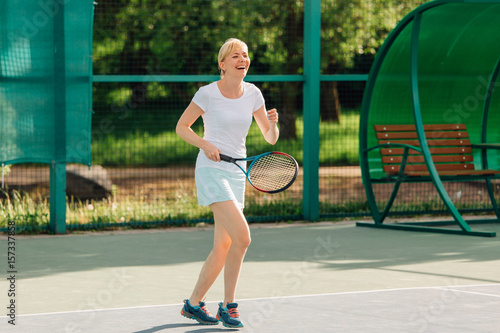 Tennis player playing on the court on a sunny day. Young sport woman training outdoors. Healthy lifestyle concept.